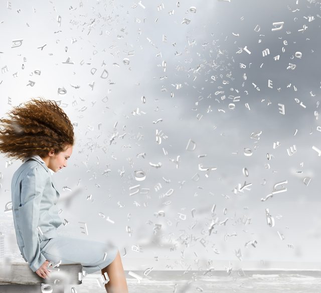 Woman sitting on edge of building with alphabets flying at her